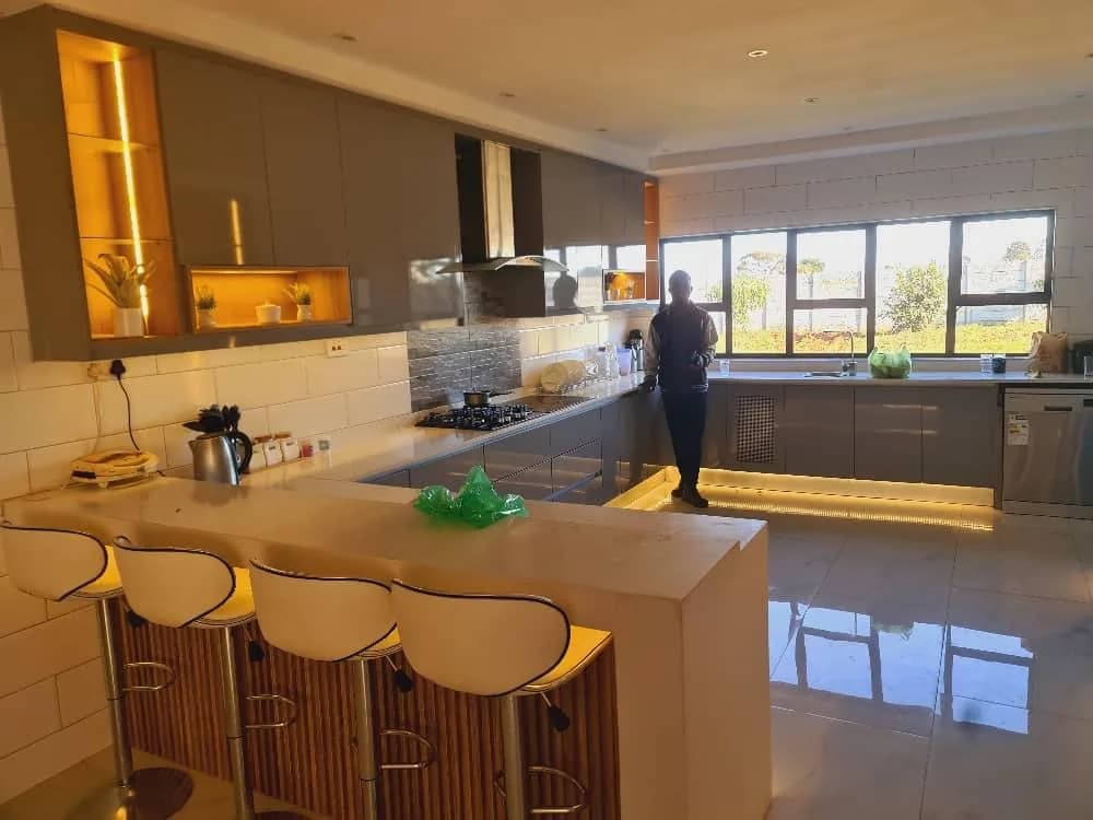 Kitchen with breakfast counter, bar stools, lit shelving and under-counter lighting