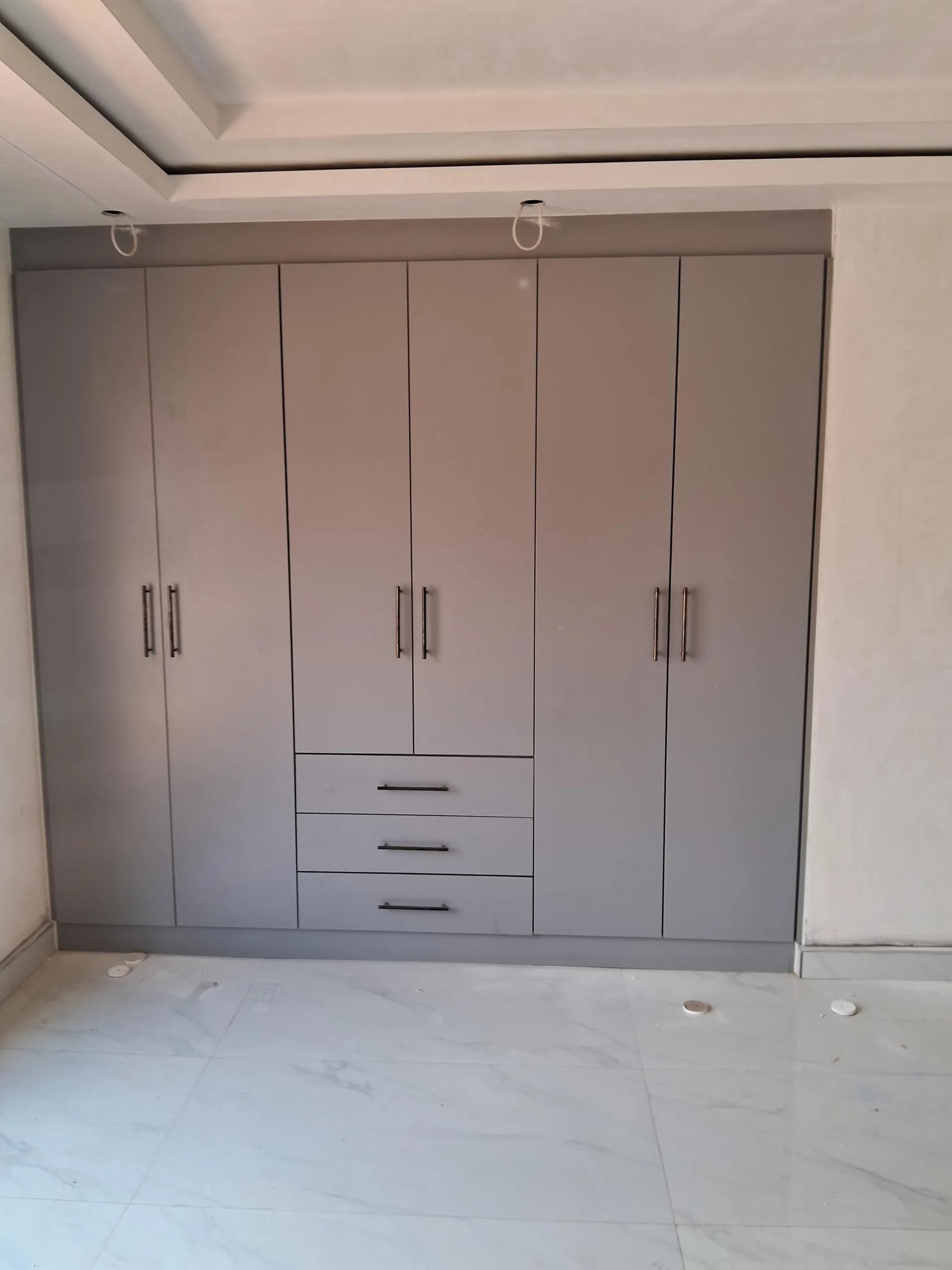 Grey built-in wardrobe with hanging space and a bank of drawers