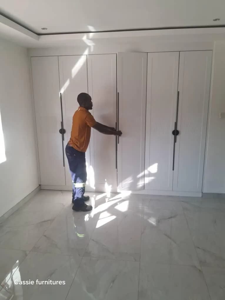 Installer fitting handles to a white built-in wardrobe